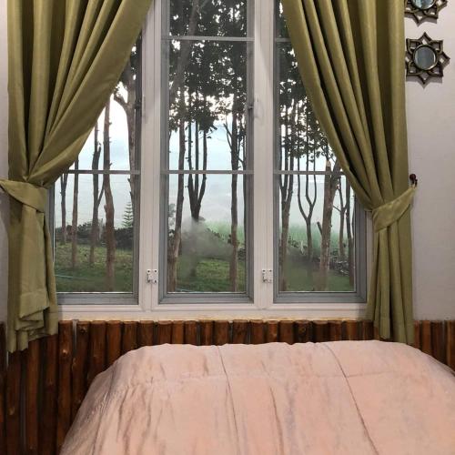a bedroom with a window with a view of trees at One khaokho homestay in Khao Kho