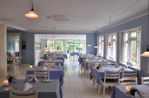 a restaurant with blue tables and chairs and windows at Hjorths Badehotel in Kandestederne