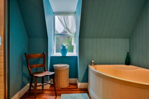 a bathroom with a tub and a chair and a window at Scatwell House in Garve