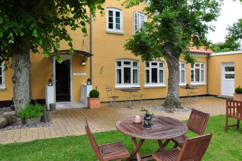 a table and chairs in front of a yellow house at Hjorths Badehotel in Kandestederne