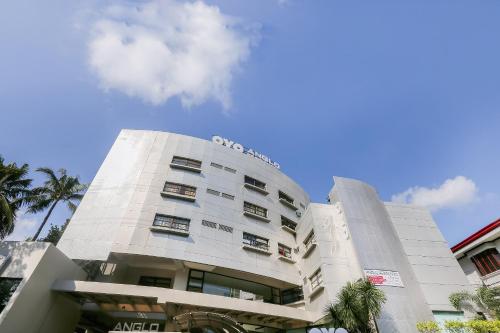 a white building with palm trees in front of it at OYO 190 Anglo Residences in Manila