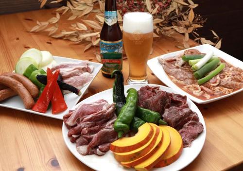 a table with two plates of food and a bottle of beer at Pension Kamifuji in Osaki