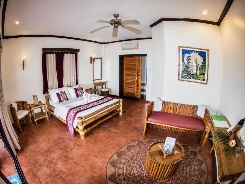 ein Schlafzimmer mit einem Bett und einem Stuhl in einem Zimmer in der Unterkunft Pura Vida Beach & Dive Resort in Dauin