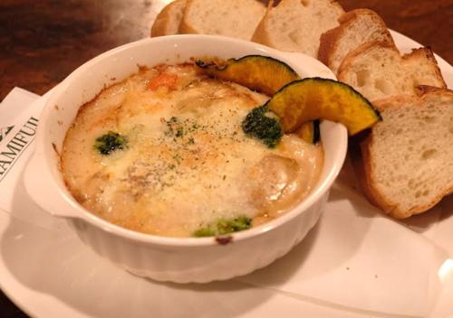 a bowl of soup with broccoli and bread on a plate at Pension Kamifuji in Osaki
