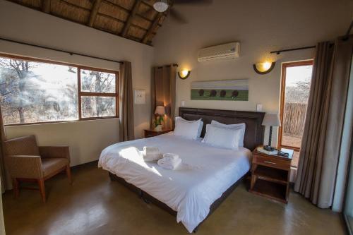 a bedroom with a large white bed and a chair at Igugu Lodge in Hoedspruit