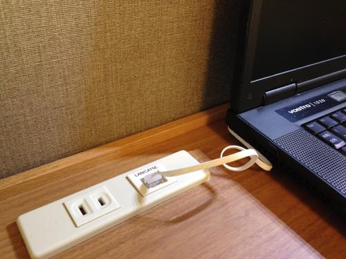a white electronic device sitting next to a laptop computer at Hiroshima Tokyu REI Hotel in Hiroshima