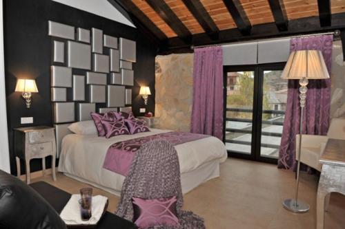 a bedroom with a large bed with purple pillows at El Balcon Del Cañon in Ucero