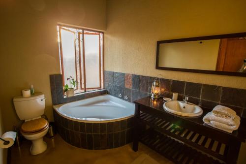 a bathroom with a tub and a toilet and a sink at Igugu Lodge in Hoedspruit