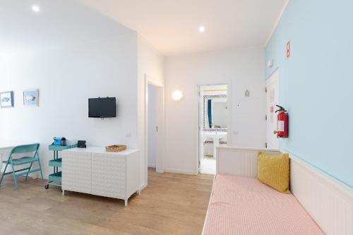 a white living room with a desk and a tv at Pé na Praia in Albufeira