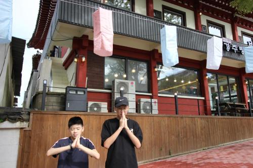 two young boys are praying in front of a building at Kids & Family Hotel in Gyeongju