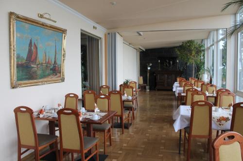ein Esszimmer mit Tischen und Stühlen und einem Gemälde an der Wand in der Unterkunft Hotel Stolteraa in Warnemünde