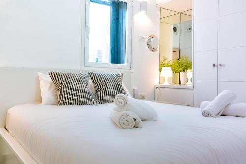 - une chambre blanche avec un grand lit blanc et des serviettes dans l'établissement Luxury Beach Tel Aviv 1 BR by Airsuite, à Tel Aviv