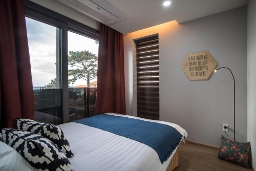 a bedroom with a bed and a window at Aewol Bada Town House in Jeju