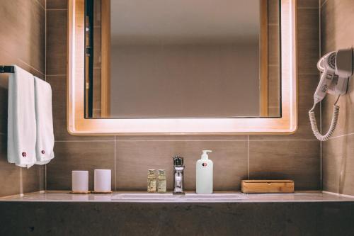 baño con lavabo con dispensador de jabón y espejo en Staybook Hotel Nitya Maharani en Nueva Delhi