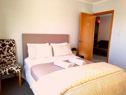 ein Schlafzimmer mit einem großen Bett und einem Stuhl in der Unterkunft Beautiful Panoramic views in Dunedin