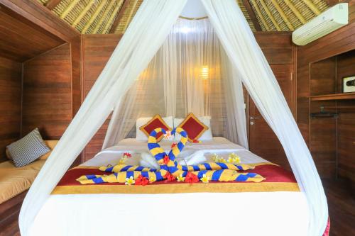 a bedroom with a bed with a mosquito net at Koji Garden Huts - CHSE Certified in Nusa Lembongan