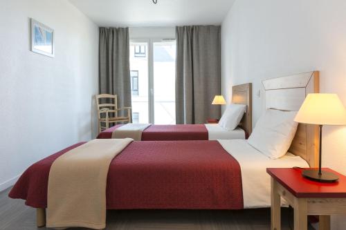 a hotel room with two beds and a table at Résidence Odalys Domaine des Roches Jaunes in Plougasnou