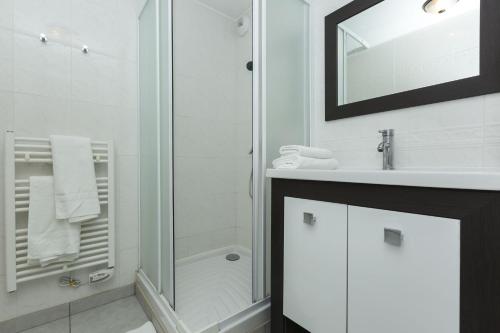 a white bathroom with a shower and a sink at Résidence Odalys Domaine des Roches Jaunes in Plougasnou