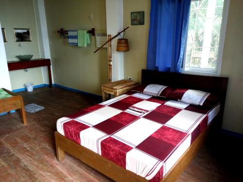 a bedroom with a bed with a red and white blanket at Paseo Del Mar Seaside Inn in Jagna