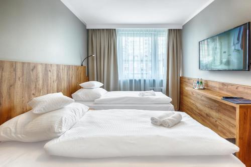 two beds in a hotel room with a tv at Hotel Tarnovia in Tarnów