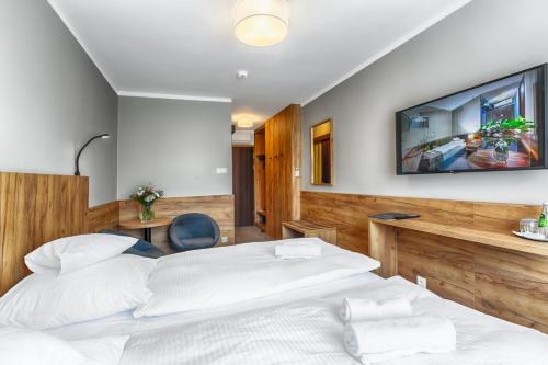 a bedroom with a bed and a tv on the wall at Hotel Tarnovia in Tarnów