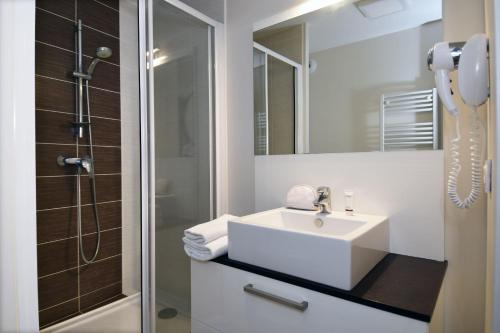 uma casa de banho branca com um lavatório e um chuveiro em Résidence Odalys Les Dunes du Soleil em La Grande-Motte