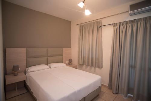 a bedroom with a white bed and a window at T'Aloni in Chortáta