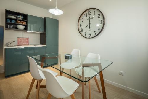 フンシャルにあるBAYLEAF Apartments - Apartamento do Tempoのダイニングルーム(ガラステーブル、白い椅子、時計付)