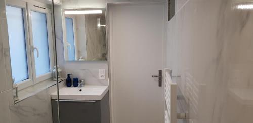 a white bathroom with a sink and a mirror at 100m2 2 chambres 8 personnes - Grand parking et terrasse privée - Proche CDG-Parc expositions-Paris-Astérix-Disney in Villepinte