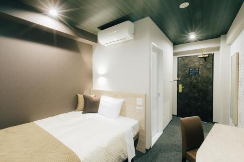 a room with two beds and a door with a window at The Celecton Kurashiki Mizushima in Kurashiki