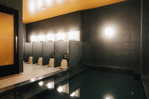 a bathroom with a swimming pool with a row of urinals at The Celecton Kurashiki Mizushima in Kurashiki