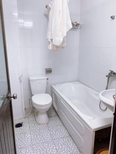 a white bathroom with a toilet and a sink at Nam Phương Hotel Sa Đéc in Sa Ðéc
