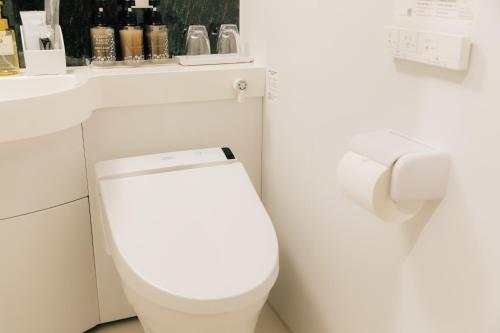 a white bathroom with a toilet and a sink at The Celecton Kurashiki Mizushima in Kurashiki