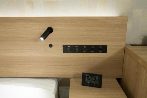 a room with a bed and an alarm clock on the wall at Shizutetsu Hotel Prezio Kyoto Shijo in Kyoto