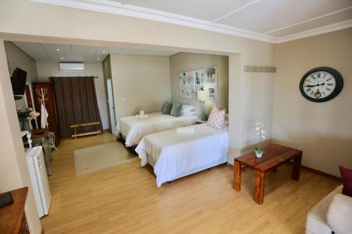 a hotel room with two beds and a clock on the wall at Boutique Guesthouse Mariental in Mariental