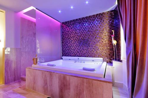 un ampio bagno con vasca e illuminazione viola di Spanish Diamond Luxury Suites & Jacuzzi a Roma