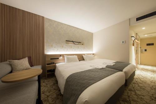 a hotel room with a large bed and a chair at Shizutetsu Hotel Prezio Kyoto Shijo in Kyoto