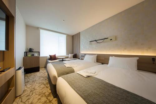 a hotel room with two beds and a television at Shizutetsu Hotel Prezio Kyoto Shijo in Kyoto