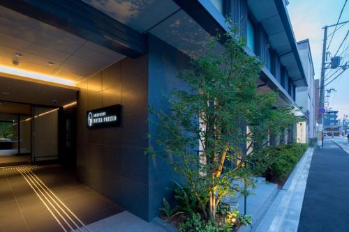 un edificio con un árbol a un lado. en Shizutetsu Hotel Prezio Kyoto Shijo en Kioto