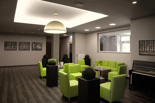 a waiting room with green chairs and a piano at Konsum Berghotel Oberhof in Oberhof
