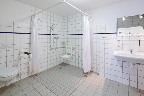uma casa de banho com um chuveiro, um WC e um lavatório. em Hotel FIT em Much