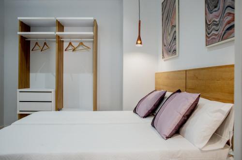 a bedroom with a white bed with purple pillows at Apartamentos Turísticos Moret 11 - 1C in Cáceres