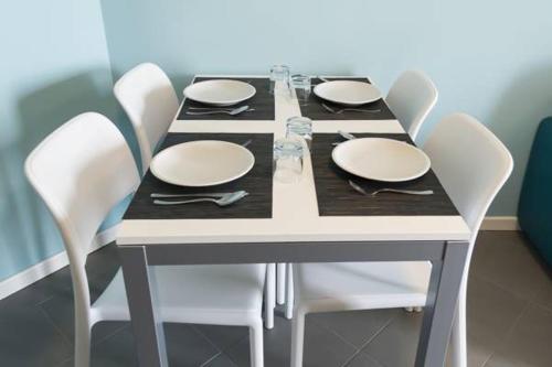 ミラノにあるPolitecnico Chique Apartmentの白いテーブル(白い椅子、皿付)