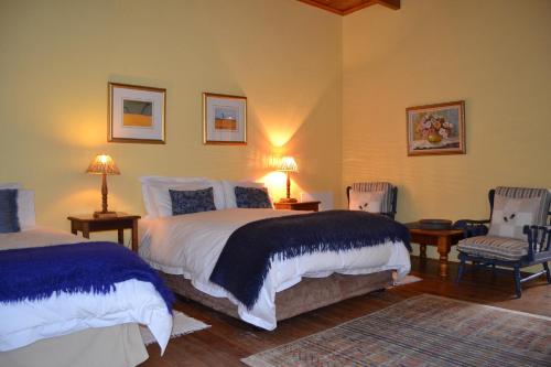 a bedroom with two beds and two chairs at Over The Mountain Guest Farm in George
