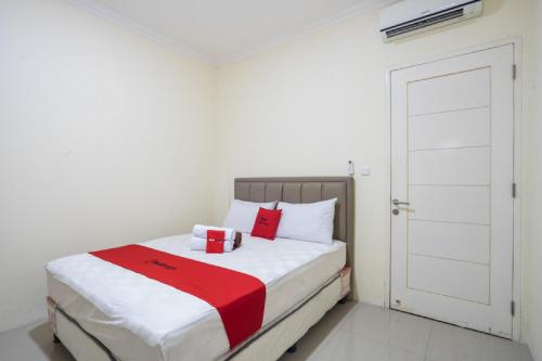 a bedroom with a bed with a red and white blanket at RedDoorz Plus near Siloam Karawaci in Tangerang