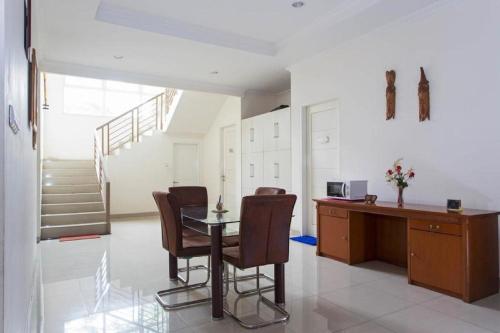 a dining room with a table and chairs and a staircase at RedDoorz Plus near Siloam Karawaci in Tangerang