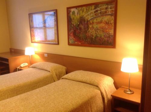 two beds in a hotel room with two lamps at Antica Trattoria dell'Uva in Monza