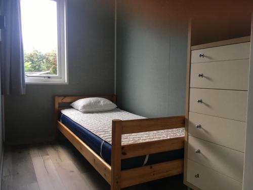 um pequeno quarto com uma cama e uma janela em Chalet Boerennest - Heerlijk chalet met overkapt terras en 3 slaapkamers - max 5 pers - 3 km van Noordzee - locatie op camping Moorhoek 10 em Rockanje