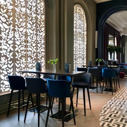 a dining room with tables and chairs and windows at The Clermont London, Victoria in London