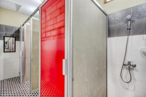 a shower with a red door in a bathroom at Home Addicts Hostel in Yogyakarta